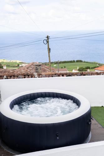 a hot tub on the side of a building with the ocean in the background at Refúgio do Sossego in Pedreira