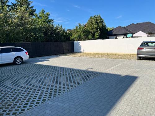 a parking lot with a white car parked next to a fence at Malu Apartman in Sárvár