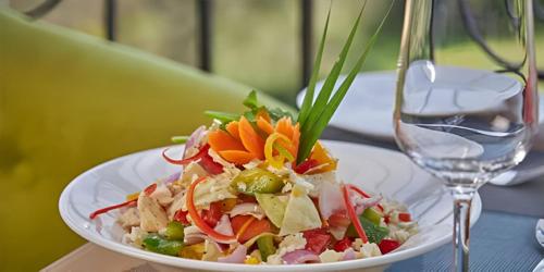 uma salada em um prato branco ao lado de um copo em Regenta INN Grand Koramangala by Royal Orchid Hotels em Bangalore