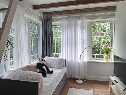 a panda bear sitting on a bed in a room with windows at Villa Manna - Charming Flat in a Historic House in Tallinn