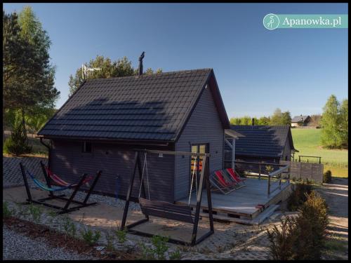a small house with a porch and a swing at APANÓWKA domki z balią jacuzzi sauna in Trzebiechowo