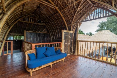 a porch with a blue couch on a wooden deck at Tricky Trees Lodges in Gili Air