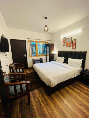 a bedroom with a large white bed and a chair at The Boho Woods Resort in Nainital