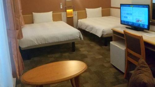 a room with two beds and a desk with a computer at Toyoko Inn Hitachi Ekimae in Hitachi