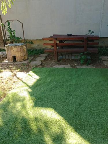 a bench and a grass yard with a bench and a table at Kis-Liget Apartman in Hajdúszoboszló