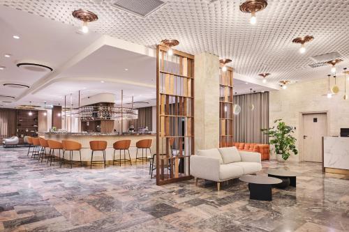a lobby with a bar and a couch and chairs at voco Katowice by IHG in Katowice