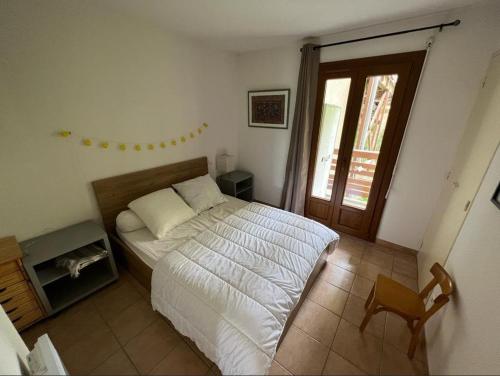 a bedroom with a bed and a chair and a window at Appartement 6 couchages proche des pistes et commerces in Les Angles