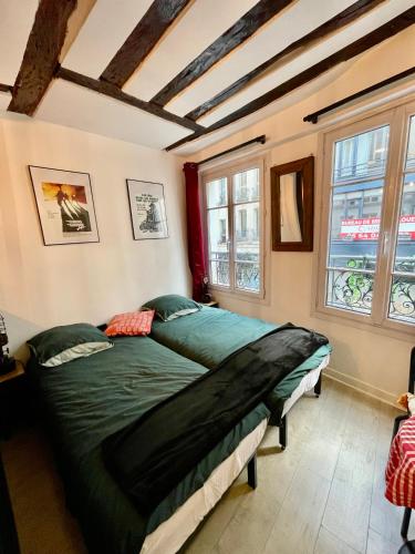 - une chambre avec un lit vert dans une pièce dotée de fenêtres dans l'établissement LE Globe, à Paris