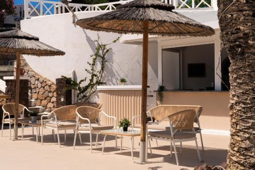 a group of chairs and a table with an umbrella at Albatros Hotel in Karterados