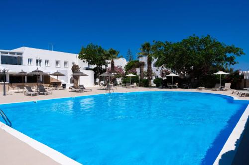 a large blue swimming pool with chairs and umbrellas at Albatros Hotel in Karterados