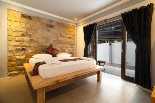 a bedroom with a bed and a stone wall at Tricky Trees Lodges in Gili Air