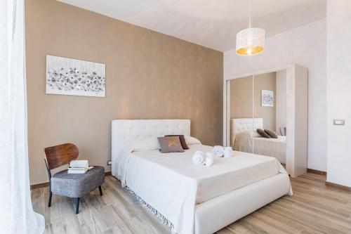 a bedroom with a large white bed and a chair at Suite Giulia - Luxury apartment in the heart of Giarre in Giarre