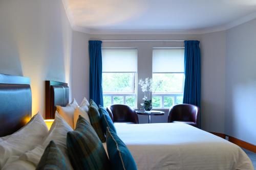 a hotel room with a bed and two windows at Glynhill Hotel & Spa near Glasgow Airport in Paisley