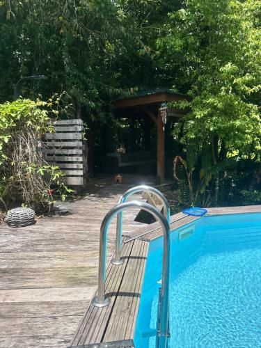 una piscina con corrimano di metallo accanto a una terrazza in legno di Villa la mahaudière vue mer a Deshaies