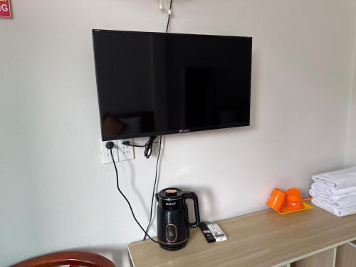 a television hanging on a wall with a coffee maker on a table at Ba Be Lake - Nhà Nghỉ Thư Nhạc in Bak Kan