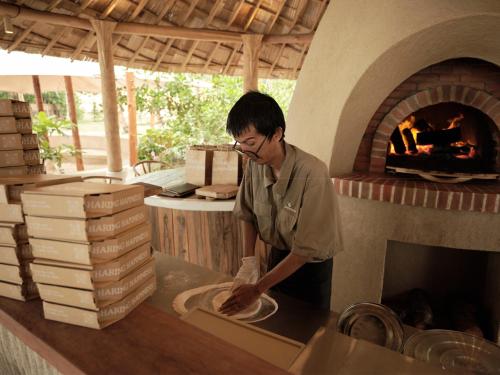 a man making a pizza in a brick oven at The Survival by Seudam in Ko Kood