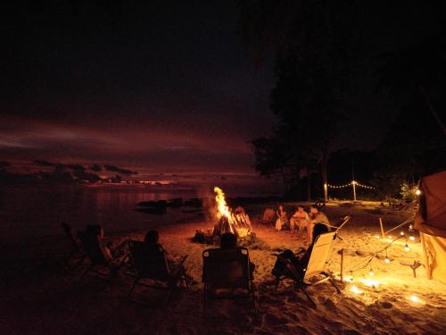 a group of people sitting around a bonfire on a beach at night at The Survival by Seudam in Ko Kood