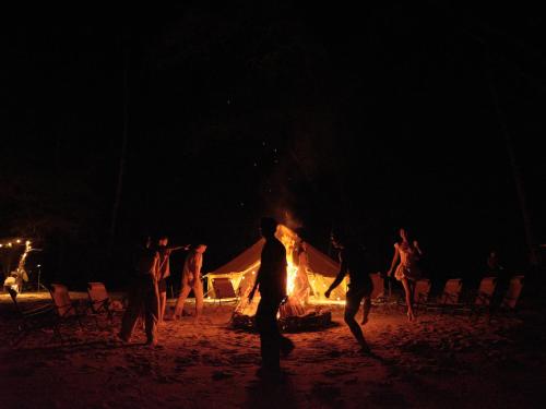a group of people standing around a fire on the beach at night at The Survival by Seudam in Ko Kood