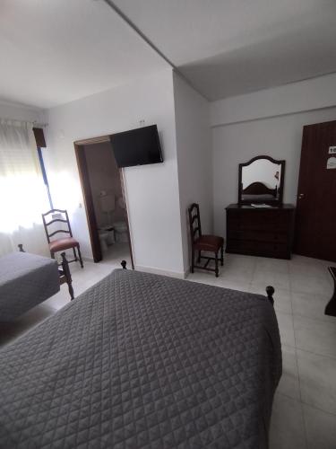 a bedroom with a bed and a dresser and a mirror at Hotel JSF in Horta
