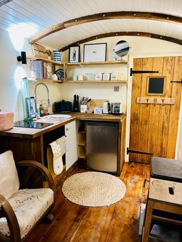 a small kitchen in a tiny house with a couch at The Railway Carriage - Blue in Glasbury