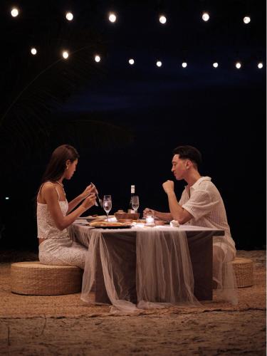 a man and woman sitting at a table with wine glasses at The Survival by Seudam in Ko Kood