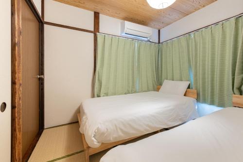 due letti in una piccola stanza con una finestra di Higashi-Ueno 3 a Tokyo