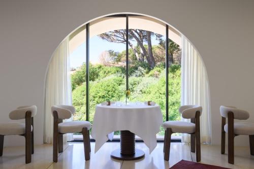 a room with a table and chairs and a large window at Vilalara Grand Hotel Algarve in Armação de Pêra