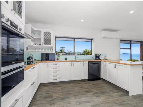 a kitchen with white cabinets and black appliances at Friesland by the beach in Somerset