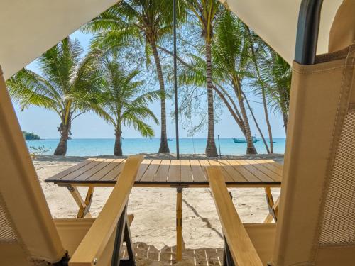 a wooden table on the beach with palm trees at The Survival by Seudam in Ko Kood