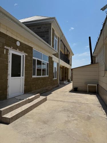 a brick building with a white door and a sidewalk at Asman in Akchiy