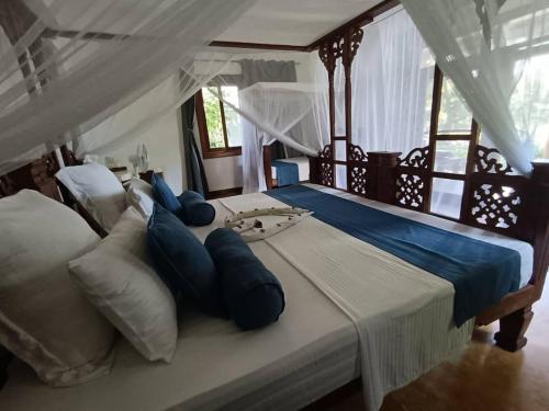 a bedroom with a large bed with blue pillows at mafiakivulinilodge in Utende