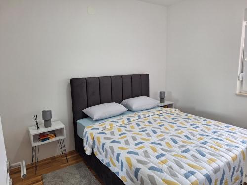 a bedroom with a bed with a black headboard and two pillows at Apartman Lory in Čapljina