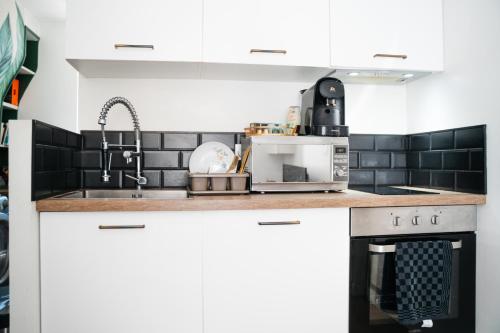 une cuisine avec des armoires blanches et un micro-ondes dans l'établissement Charmant T3 Paris Stade de France, à Saint-Denis