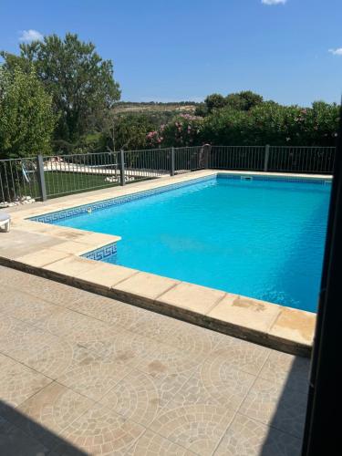 a large blue swimming pool with a fence at Maison 6 personnes avec piscine terrain arboré clôturé in Vallabrix