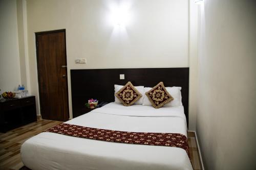 a bedroom with a large white bed with two pillows at Lumbini Zambala Hotel in Lumbini
