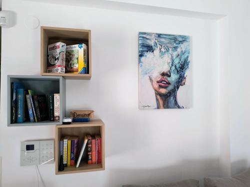 a painting of a woman on a wall next to books at Momo's House in Nikiti