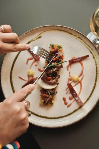 a person is eating a plate of food with forks at Hôtel BelleVue in Bréhat