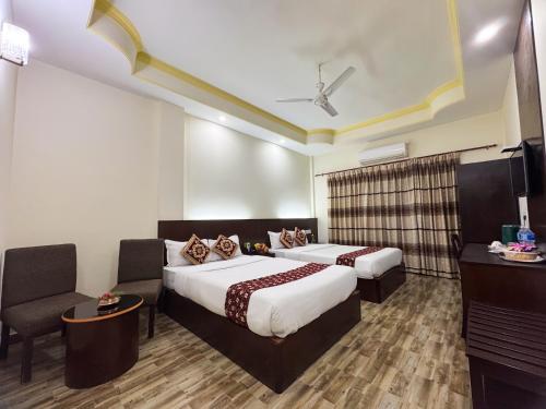 a hotel room with two beds and a chair at Lumbini Zambala Hotel in Lumbini