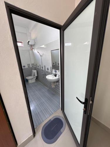 a bathroom with a door open to a toilet and a sink at Ba Be Lake - Nhà Nghỉ Thư Nhạc in Bak Kan