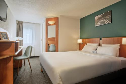 a hotel room with a large bed and a desk at Kyriad Paris Sud Les Ulis Courtaboeuf in Les Ulis