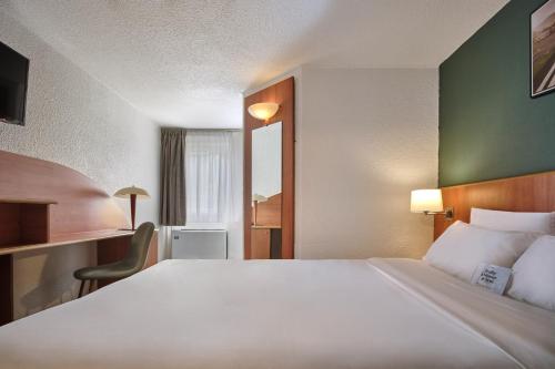 a hotel room with a large bed and a desk at Kyriad Paris Sud Les Ulis Courtaboeuf in Les Ulis