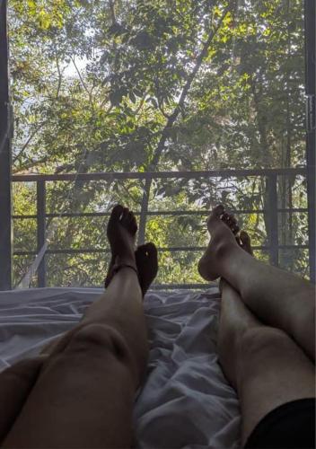 a man laying on a bed looking out a window at Nature World Jungle Paradise in Udawalawe