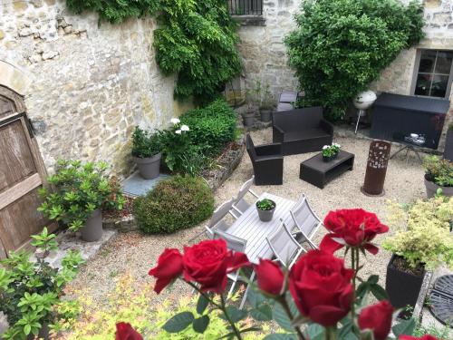 - un jardin avec des roses rouges, une table et des chaises dans l'établissement La Tour de Flandre, à Rousseloy