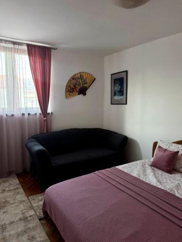 a bedroom with a bed and a couch next to a window at Apartman M5 in Cetinje
