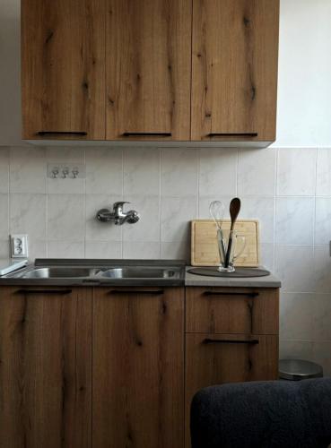a kitchen with wooden cabinets and a sink with utensils at Apartman M5 in Cetinje