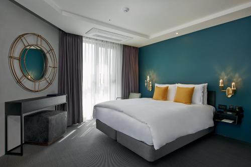 una camera da letto con un letto grande e una parete blu di Maxx Jeju, a member of H Rewards a Jeju