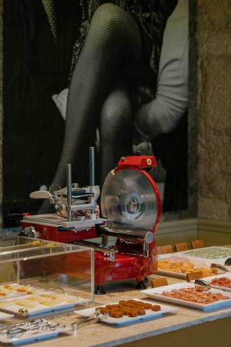 Una mesa llena de pasteles sobre una mesa con una máquina roja. en Vila Foz Hotel & SPA - member of Design Hotels, en Oporto