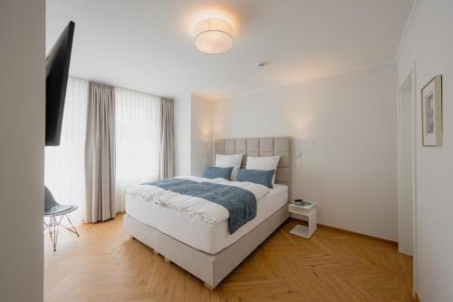 a white bedroom with a bed and a television at Markt22 - Exklusive Stadtapartments in Lingen