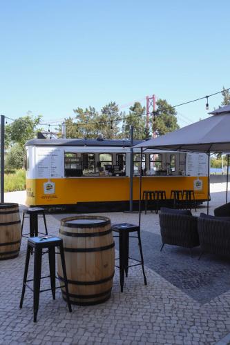 a yellow bus parked next to tables and a barrel at Hyatt Regency Lisbon in Lisbon