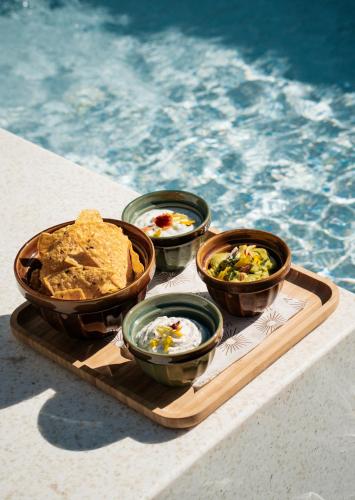 a tray with four bowls of food next to a pool at Hyatt Regency Lisbon in Lisbon